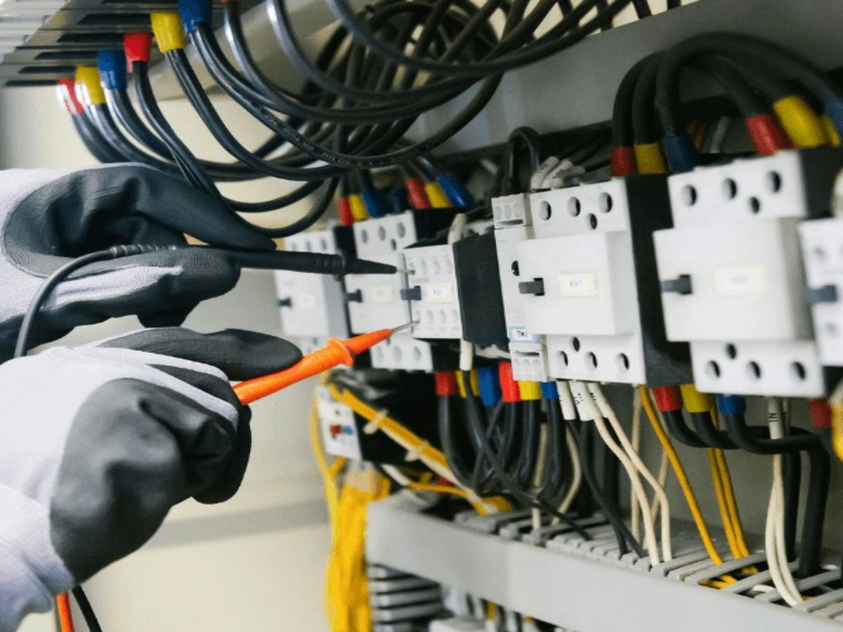 Een elektricien meet de spanning in een verdeelbord